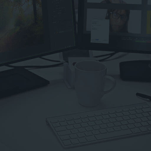 Schreibtisch im Home-Office mit zwei Computerbildschirmen während einer Online-Schulung. Auf einem Monitor kann der Bildschirm des Dozenten verfolgt werden auf dem Zweitmonitor sind die Videoansichten der Kursteilnehmer zu sehen.