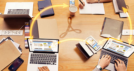 Mehrere Personen sitzen an einem Konferenztisch vor Laptops, Tablet-Computern und Smartphones und tauschen PDF-Dokumente aus oder arbeiten gemeinsam an einem PDF.