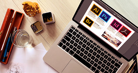 Laptop auf dessen Bildschirm die Programmicons von Adobe Illustrator, Photoshop, InDesign, Acrobat und Bridge zu sehen sind.