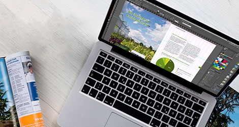 Laptop auf dessen Bildschirm ein Magazinlayout in Adobe InDesign zu sehen ist